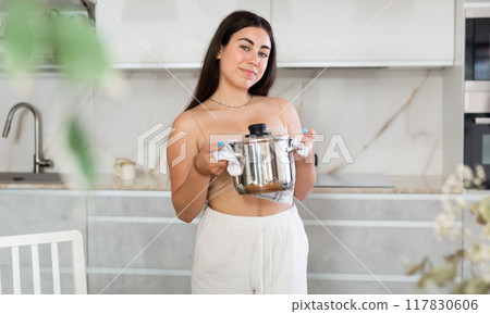 Young woman posing with saucepan in kitchen at home 117830606