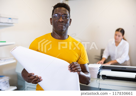 Middle-aged African American man holding large format paper whatman in a roll in the middle of the typography 117830661