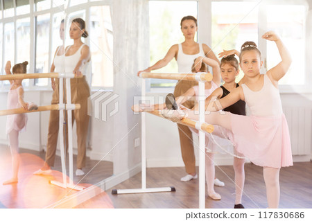Girls dancers doing stretching at barre Girls dancers doing stretching at barre 117830686