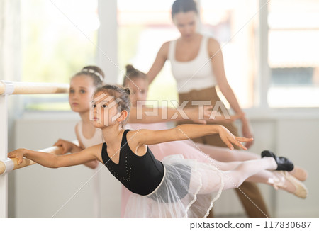 Little girls ballet lovers learn to perform arabesque pose in choreography studio 117830687