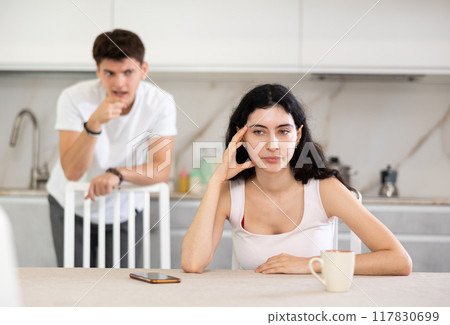 Young guy quarrels with young woman in kitchen Young guy quarrels with young woman in kitchen 117830699