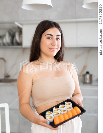Young woman posing with set of rolls in kitchen 117830830