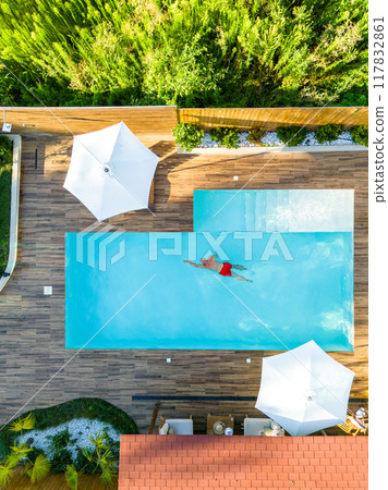 Top-Down Shot of Man Swimming in High-End Villa Pool. Concept of serene lifestyle and upscale comfort Top-Down Shot of Man Swimming in High-End Villa Pool. Concept of serene lifestyle and upscale comfort 117832861