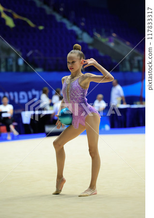A rhythmic gymnast performs gracefully with a ball, showing artistry, dedication, and flexibility 117833317