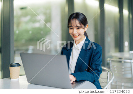 A woman using a laptop on a cafe terrace A woman using a laptop on a cafe terrace 117834053