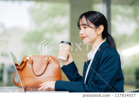 A woman using a laptop on a cafe terrace 117834057