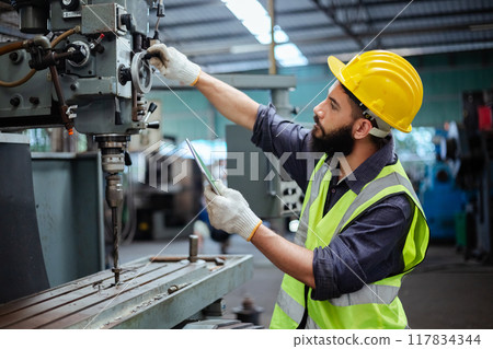 Man technician worker using tablet control setting up operating electric drill 117834344