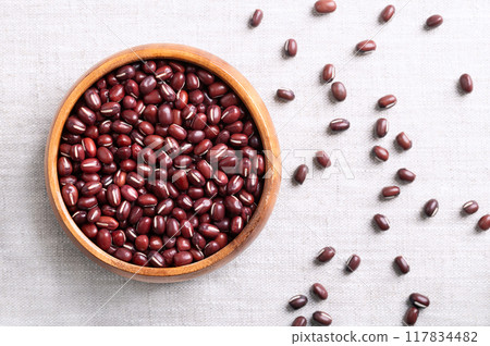Adzuki beans in a wooden bowl on linen fabric. Also known as azuki, aduki, red, or red mung bean. Dried seeds of Vigna angularis, a member of the legume family Fabaceae, used in East Asian cuisine. 117834482
