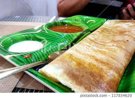 South indian food crispy Masala Dosa with sambar and chutney on banana leaf style plate. selective focus South indian food crispy Masala Dosa with sambar and chutney on banana leaf style plate. selective focus 117834620