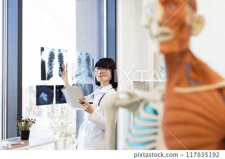 Doctor reviewing patient x-rays in office with anatomical model 117835192