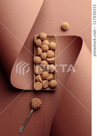 Chocolate truffles and spoon with cocoa powder. 117836313