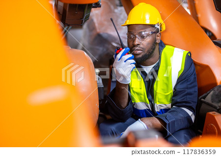 African American man engineer standing holding walkie talkie at automation robot arms machine African American man engineer standing holding walkie talkie at automation robot arms machine 117836359