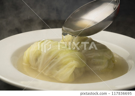 Rolled cabbage: Pouring soup onto rolled cabbage on a plate 117836695