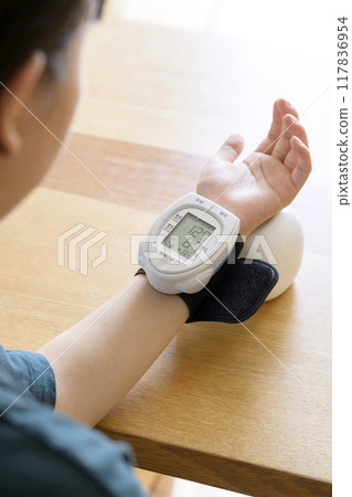 Woman measuring blood pressure at home 117836954
