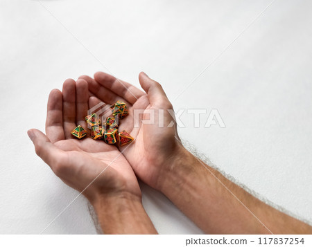 Hands gently holding colorful polyhedral dice on white background Hands gently holding colorful polyhedral dice on white background 117837254