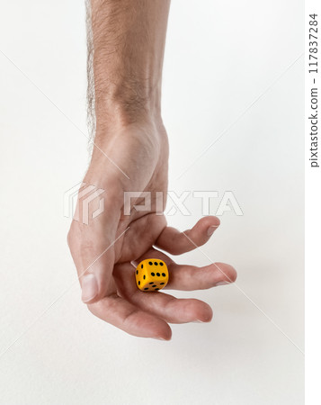 Hand holding yellow die: minimalist concept of chance and decision-making Hand holding yellow die: minimalist concept of chance and decision-making 117837284