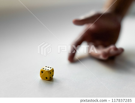 Hand in motion with yellow dice on a white surface capturing chance and luck Hand in motion with yellow dice on a white surface capturing chance and luck 117837285