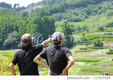 Two men looking at the mountain scenery with rice terraces. Rice terraces in Shikazato (Shikazato, Hoshino Village, Yame City) Two men looking at the mountain scenery with rice terraces. Rice terraces in Shikazato (Shikazato, Hoshino Village, Yame City) 117837429