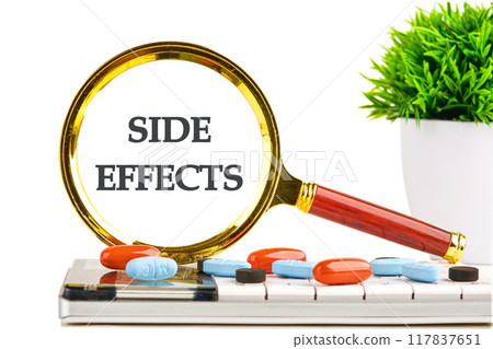 Medical concept. The inscription SIDE EFFECTS through a magnifying glass in a composition with a calculator, tablets and a plant on a white background 117837651