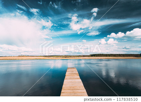 Old Wooden Boards Pier On Calm Water Of Lake Or River At Evening Or Morning Time. Forest On Other Side. Landscape 117838510