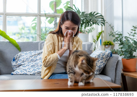 young woman has sneezing and burning nose due to an allergic reaction to owning cat. 117838693