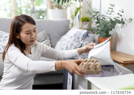 Asian young female sitting at home separating paper and plastic waste. Asian young female sitting at home separating paper and plastic waste. 117838734