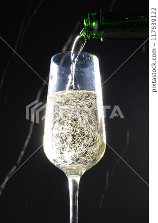 Pour well-chilled champagne (sparkling wine) into a flute glass 117839122