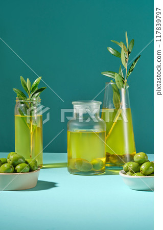 Scene for display of organic natural cosmetic products - empty space with fresh olive bowl and olive oil on green background. Blank space to display packaging mockup Scene for display of organic natural cosmetic products - empty space with fresh olive bowl and olive oil on green background. Blank space to display packaging mockup 117839797