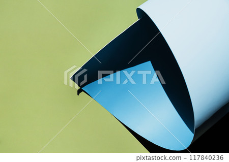 Curled blue paper creating shadows on green background. 117840236