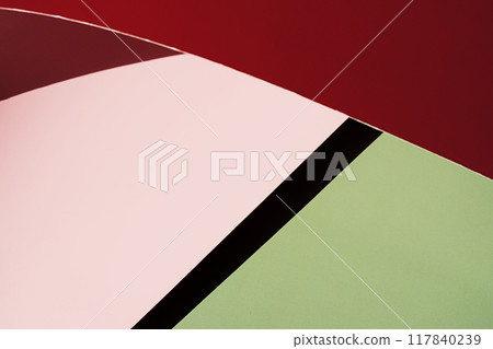 Close up of curved red and pink paper against green background. Close up of curved red and pink paper against green background. 117840239