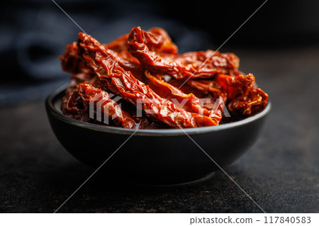 Sun dried red tomatoes in bowl on black table. Sun dried red tomatoes in bowl on black table. 117840583