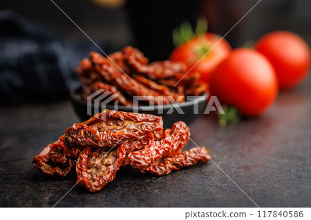 Sun dried red tomatoes on black table. 117840586