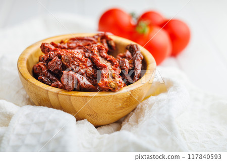 Sun dried red tomatoes in bowl on white table. 117840593