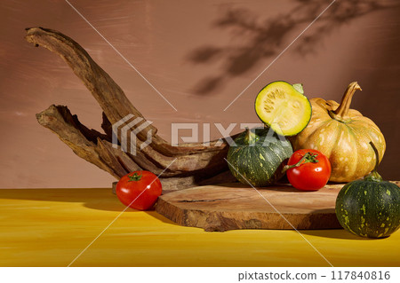 Some fresh vegetables consist of pumpkin and tomato decorated around a blank wooden tray for product presentation. Photo of front view for healthy food advertising 117840816