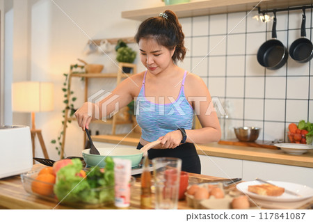 Young fitness woman preparing healthy meal on kitchen counter. Healthy lifestyle concept 117841087