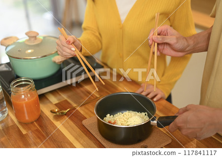 Close up shot of young couple sharing a bowl of instant noodles enjoying a casual meal in kitchen 117841117