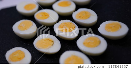 Halves of boiled chicken eggs on a black background Halves of boiled chicken eggs on a black background 117841367