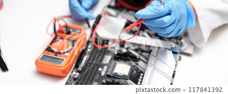 Hands with a multimeter to check electronic equipment 117841392
