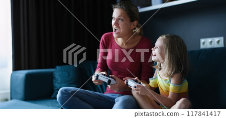 Little girl with her mother play video games, close-up Little girl with her mother play video games, close-up 117841417