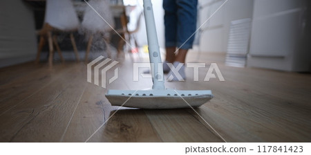 A steam mop washes the parquet on the floor of the house A steam mop washes the parquet on the floor of the house 117841423