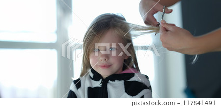 Sweet little girl cutting a lock of hair Sweet little girl cutting a lock of hair 117841491