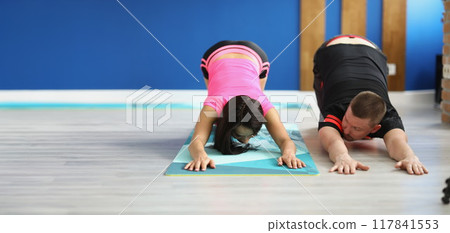 A man and a woman on the floor doing back stretches A man and a woman on the floor doing back stretches 117841553