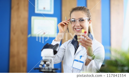 Young woman laboratory assistant smiling holding a flask 117841554