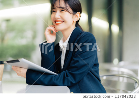 Woman using a tablet on a cafe terrace 117842028
