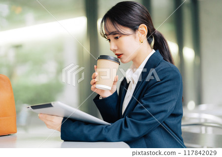 Woman using a tablet on a cafe terrace 117842029