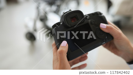 Female hands are holding a black modern camera 117842402