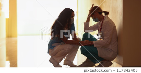 A female doctor calms down a tired colleague 117842403