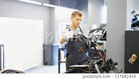 A man mechanic repairs the steering wheel of a motorcycle 117842459