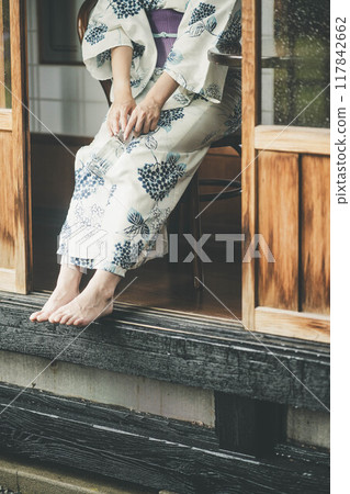 一位穿著浴衣的年輕女子坐在門廊上 117842662