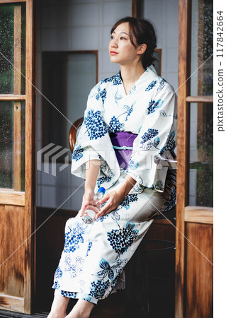 一位穿著浴衣的年輕女子坐在門廊上 117842664